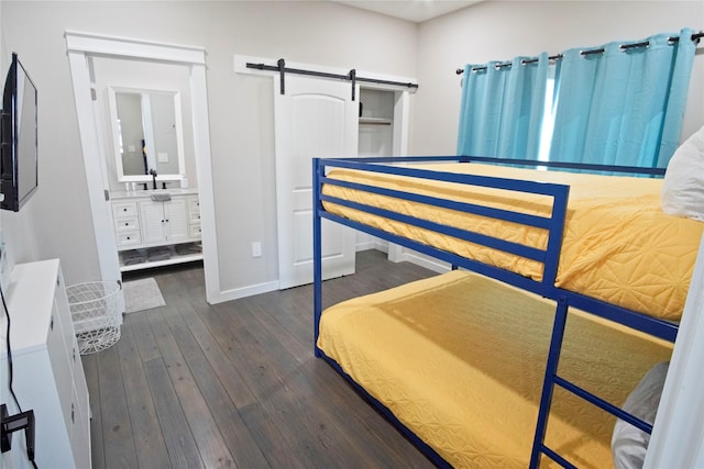 bedroom with dark hardwood / wood-style flooring, sink, connected bathroom, and a barn door