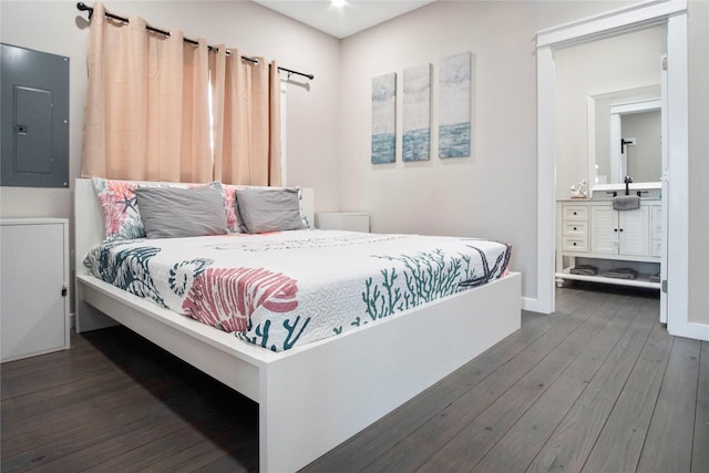 bedroom with sink, ensuite bath, dark wood-type flooring, and electric panel