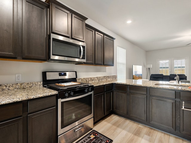 kitchen with sink, stainless steel appliances, light hardwood / wood-style flooring, and dark brown cabinetry