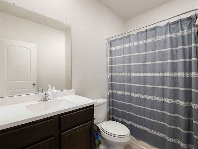 bathroom featuring toilet, walk in shower, and vanity