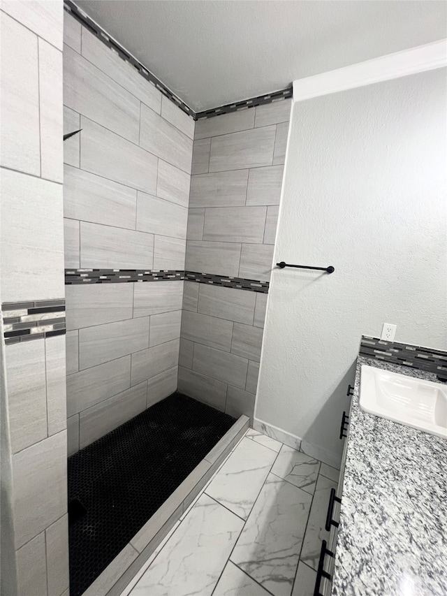 bathroom with tile patterned floors, vanity, and tiled shower