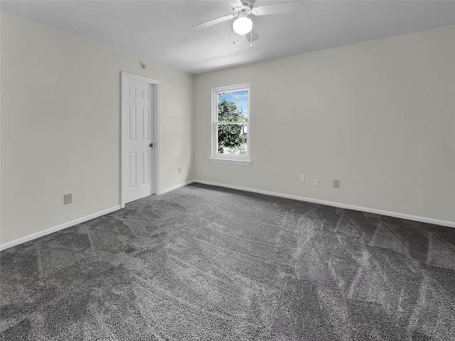 empty room featuring ceiling fan and dark colored carpet