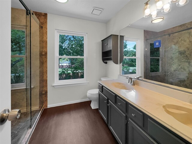 bathroom featuring hardwood / wood-style floors, double vanity, a shower with door, and toilet