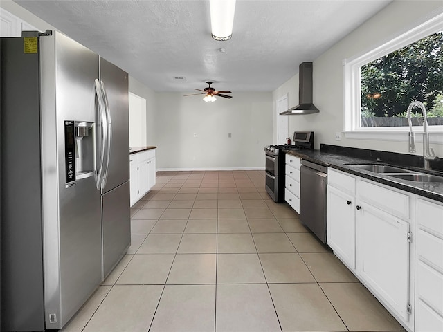 kitchen featuring appliances with stainless steel finishes, sink, light tile patterned floors, wall chimney exhaust hood, and white cabinets