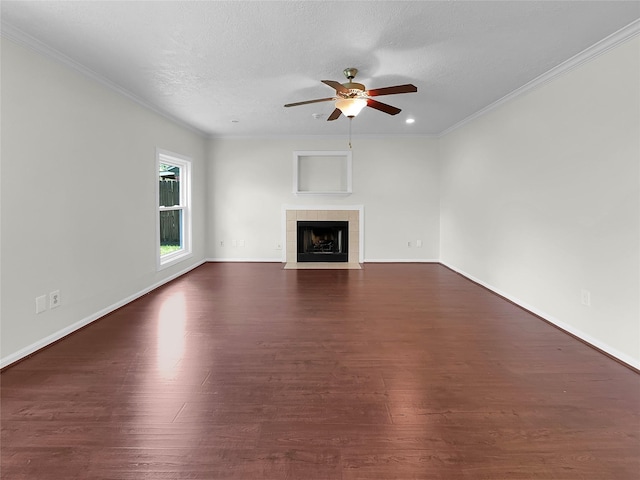 unfurnished living room featuring a tile fireplace, a textured ceiling, ceiling fan, ornamental molding, and dark hardwood / wood-style floors