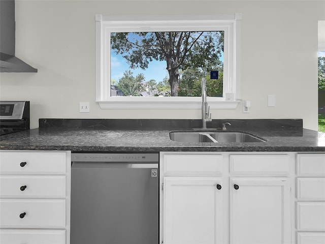 kitchen featuring plenty of natural light, wall chimney exhaust hood, white cabinets, stainless steel dishwasher, and sink