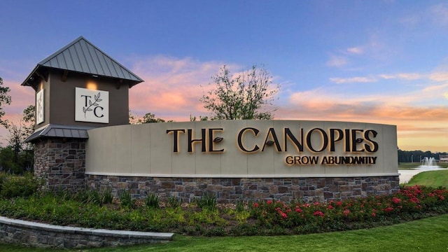 community / neighborhood sign featuring a lawn and a water view