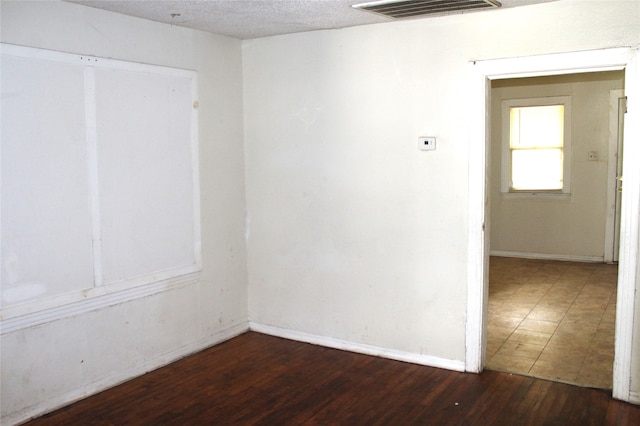 spare room with a textured ceiling and dark hardwood / wood-style flooring