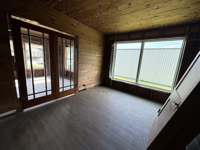 spare room with wooden ceiling, wood-type flooring, french doors, and wooden walls