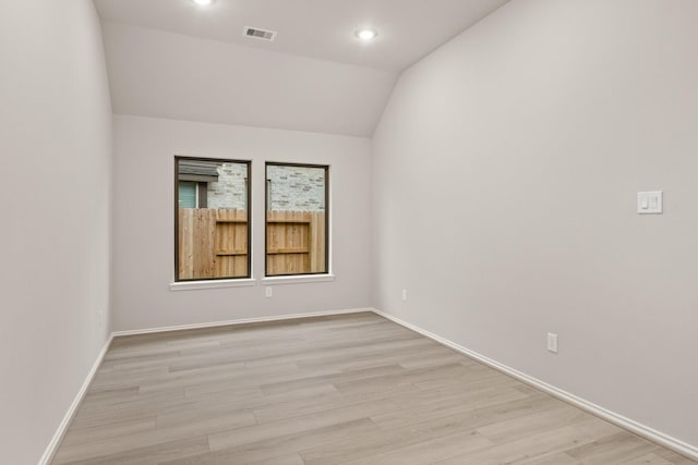 spare room featuring light hardwood / wood-style floors and vaulted ceiling