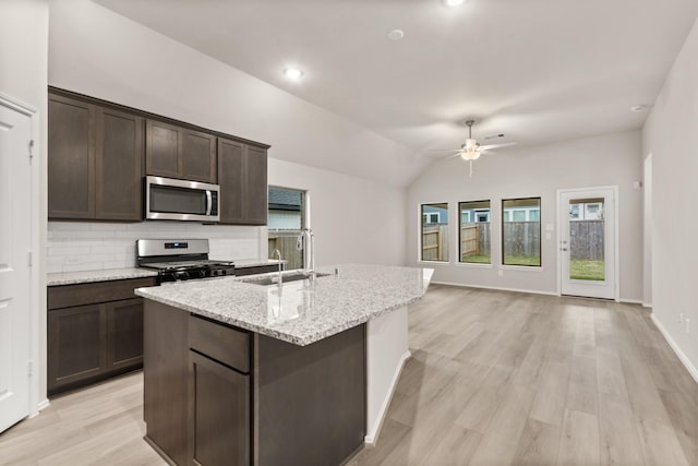 kitchen featuring a kitchen island with sink, stainless steel appliances, dark brown cabinetry, sink, and lofted ceiling