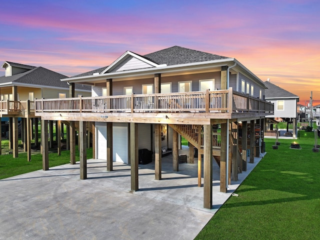 back house at dusk with a wooden deck and a lawn