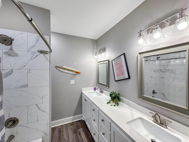 full bathroom with double vanity, walk in shower, wood finished floors, and a sink