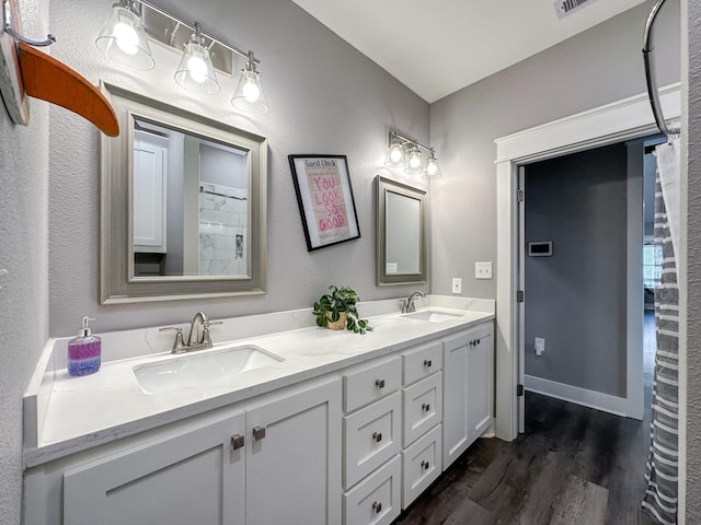 full bath with a sink, baseboards, wood finished floors, and double vanity