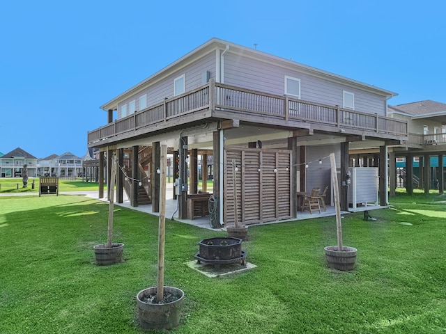 rear view of house featuring a yard, a fire pit, a wooden deck, and a patio area