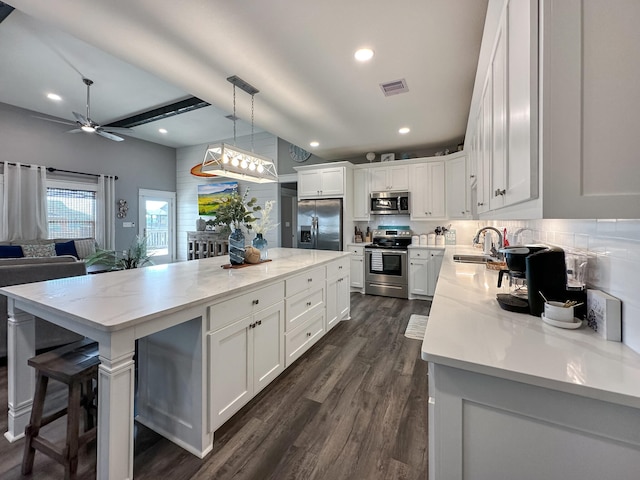 kitchen with appliances with stainless steel finishes, sink, dark hardwood / wood-style floors, and a kitchen island