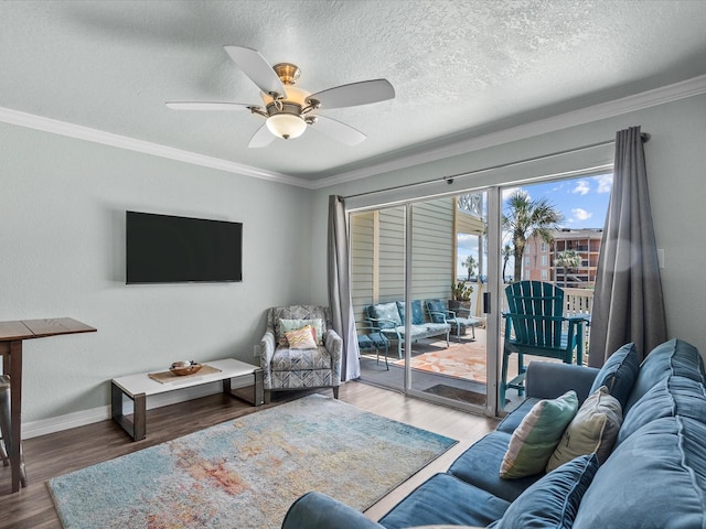 living room with baseboards, ceiling fan, wood finished floors, crown molding, and a textured ceiling