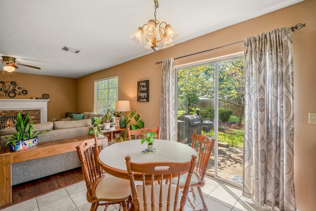 tiled dining area featuring ceiling fan with notable chandelier