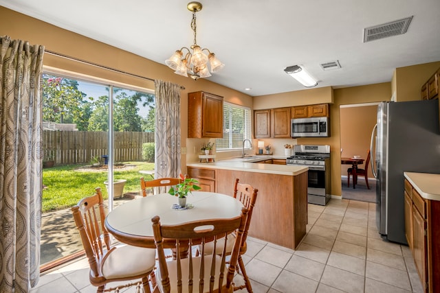 kitchen with appliances with stainless steel finishes, light tile patterned floors, hanging light fixtures, and sink