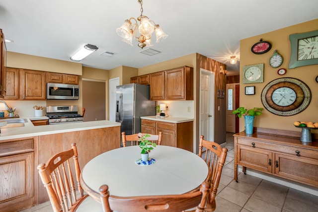 kitchen featuring pendant lighting, sink, light tile patterned floors, appliances with stainless steel finishes, and a chandelier