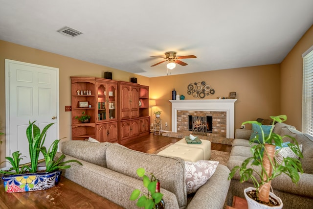 living room featuring ceiling fan, a fireplace, and wood-type flooring