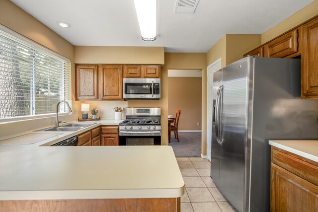 kitchen featuring kitchen peninsula, sink, stainless steel appliances, and light tile patterned flooring