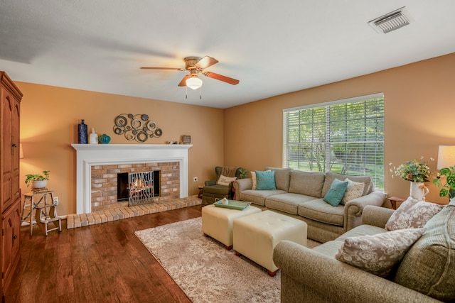 living room with a fireplace, ceiling fan, and dark wood-type flooring