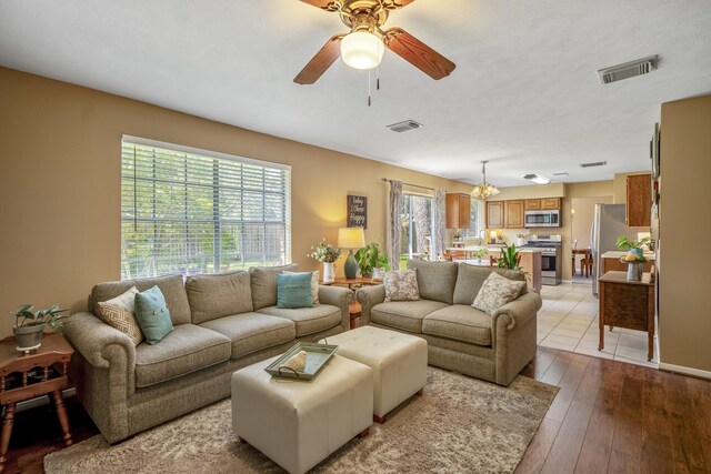 living room featuring light hardwood / wood-style floors and ceiling fan with notable chandelier