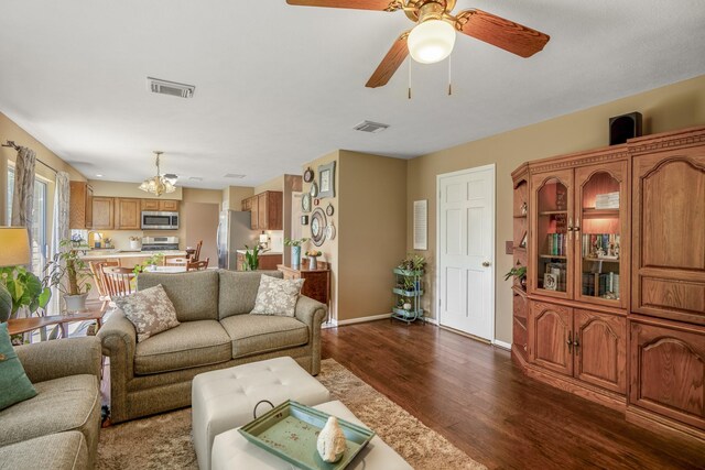 living room featuring dark hardwood / wood-style flooring and ceiling fan with notable chandelier