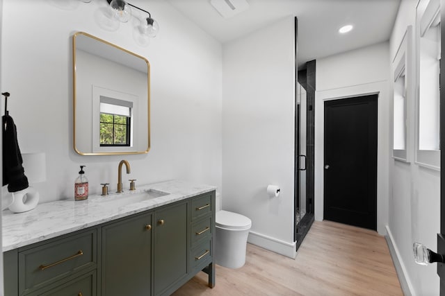 bathroom featuring vanity, a shower with door, toilet, and hardwood / wood-style flooring