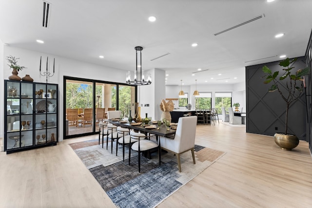 dining space with a notable chandelier and light hardwood / wood-style flooring