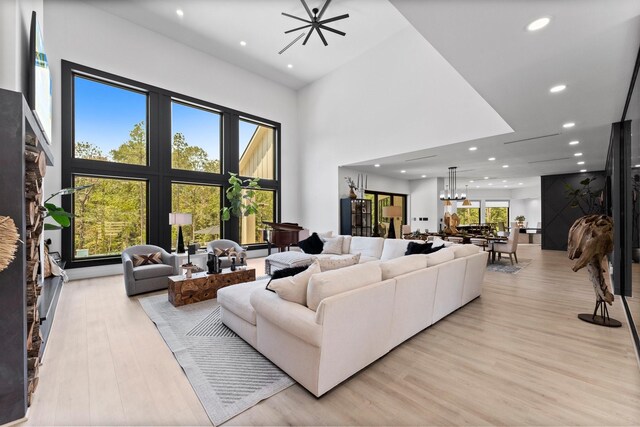 living room featuring a wealth of natural light, a chandelier, light hardwood / wood-style floors, and a towering ceiling