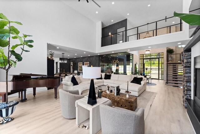 living room with light wood-type flooring, a chandelier, and a high ceiling