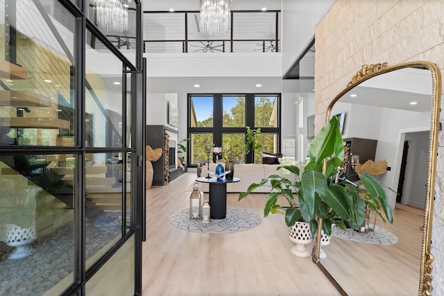 interior space featuring light hardwood / wood-style flooring, an inviting chandelier, and a high ceiling