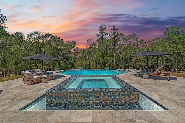 pool at dusk featuring an in ground hot tub and a patio