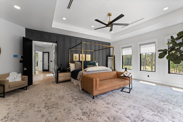 bedroom featuring a tray ceiling, light tile patterned floors, and multiple windows