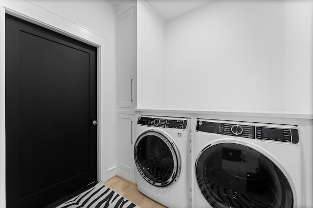 clothes washing area featuring cabinets, light wood-type flooring, and washing machine and clothes dryer