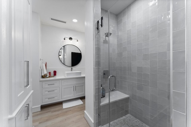 bathroom featuring walk in shower, vanity, and wood-type flooring