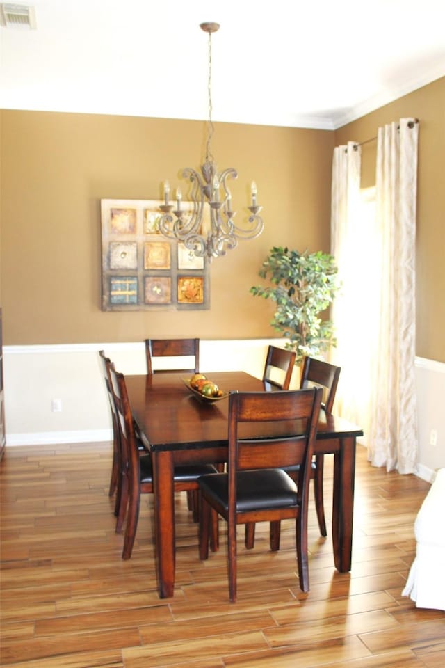 dining space with ornamental molding, light hardwood / wood-style floors, and an inviting chandelier