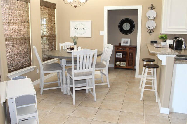 dining area with sink, light tile patterned flooring, and an inviting chandelier