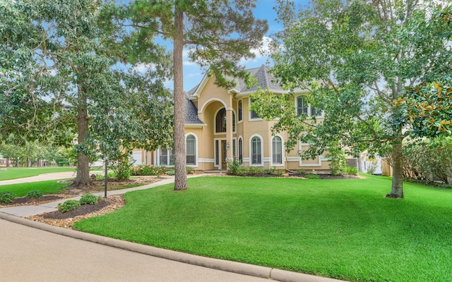 view of front facade with a shingled roof, a front lawn, stucco siding, a garage, and driveway