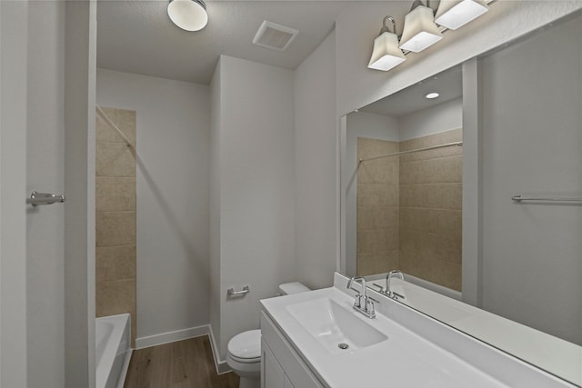 full bathroom with a textured ceiling, toilet, hardwood / wood-style floors, tiled shower / bath, and vanity