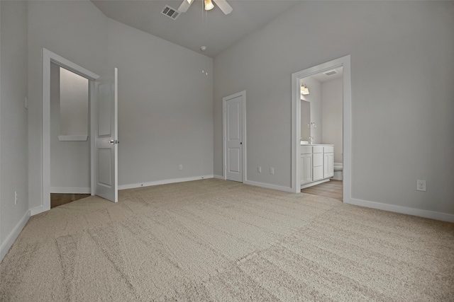 unfurnished bedroom featuring ceiling fan, connected bathroom, light colored carpet, and lofted ceiling