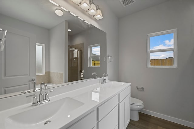 bathroom with dual vanity, wood-type flooring, a wealth of natural light, and toilet