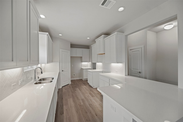 kitchen with white cabinetry, tasteful backsplash, sink, and light hardwood / wood-style floors