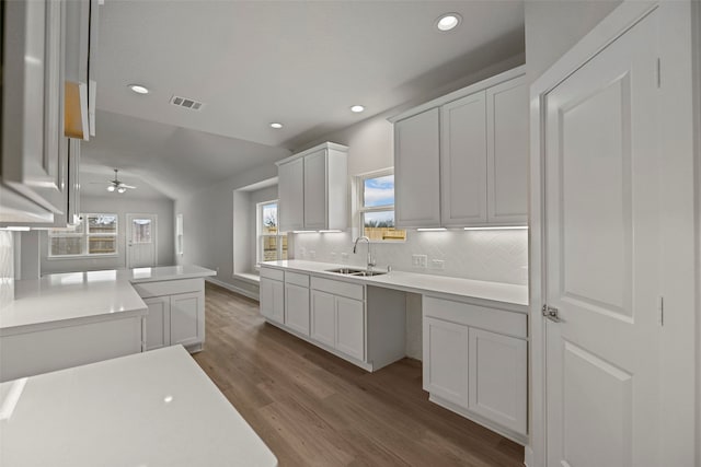 kitchen featuring lofted ceiling, white cabinets, sink, tasteful backsplash, and hardwood / wood-style flooring