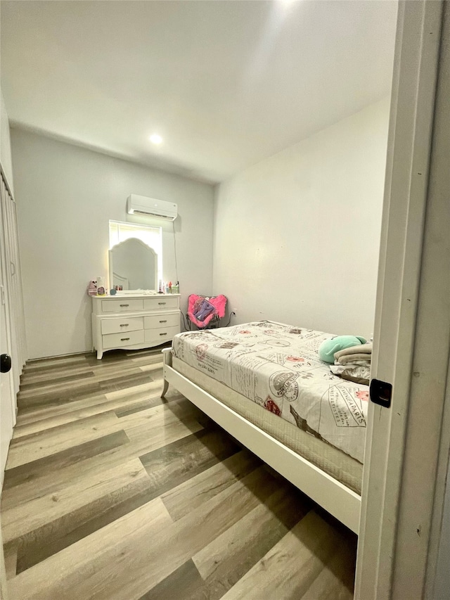 bedroom featuring light hardwood / wood-style flooring and an AC wall unit