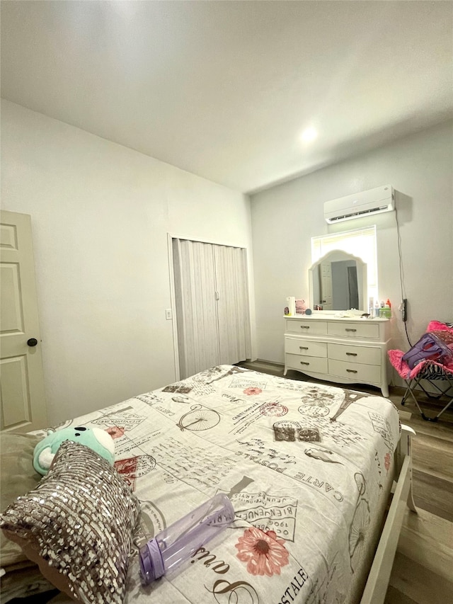 bedroom with a wall mounted AC and wood-type flooring