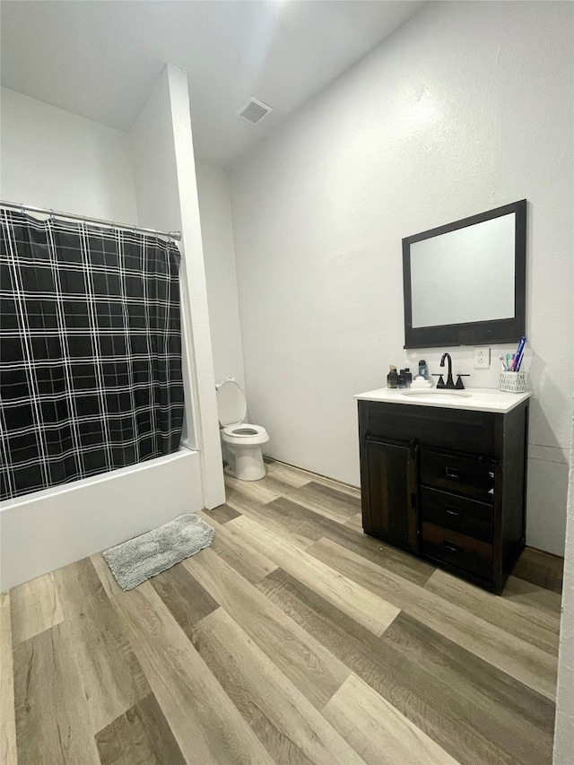 full bathroom with shower / bath combination with curtain, toilet, hardwood / wood-style flooring, and vanity