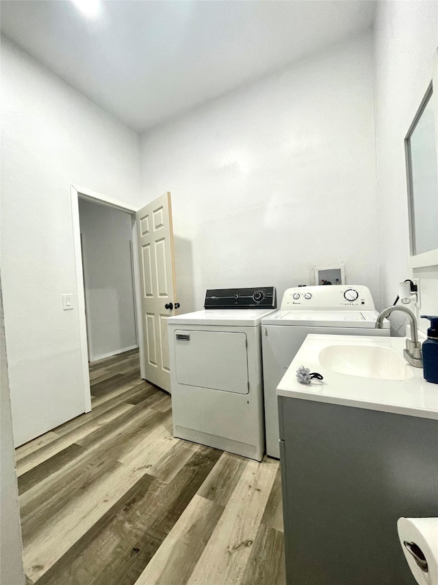 laundry room with washer and clothes dryer, sink, and light wood-type flooring